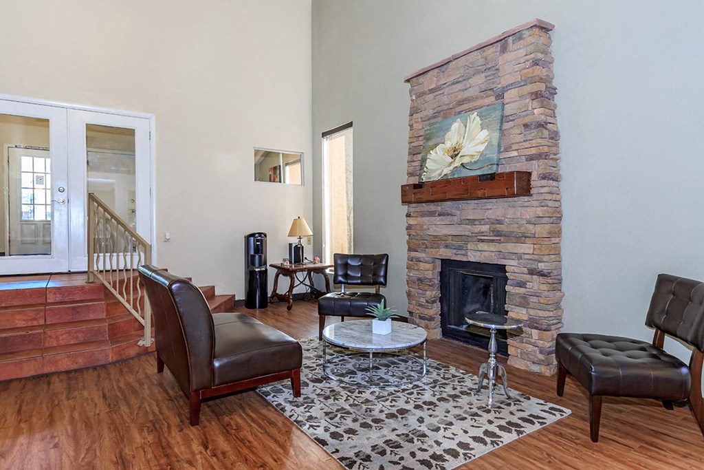 A living room with a stone fireplace and a painting of a white flower above it.