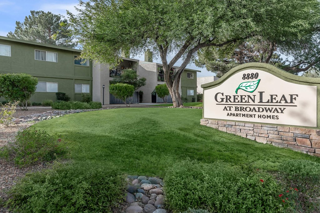 A sign for Green Leaf Apartments is in front of a building.
