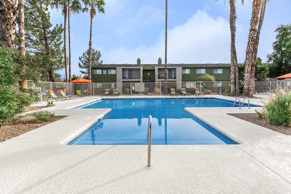 A swimming pool surrounded by palm trees and a building in the background.