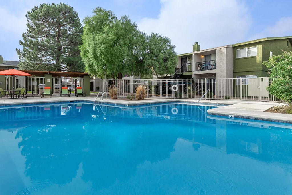 A swimming pool in front of a building with a fence around it.