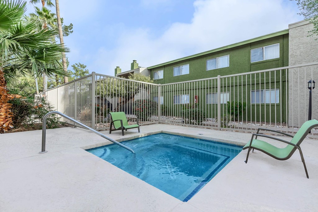 A pool surrounded by a fence and chairs.