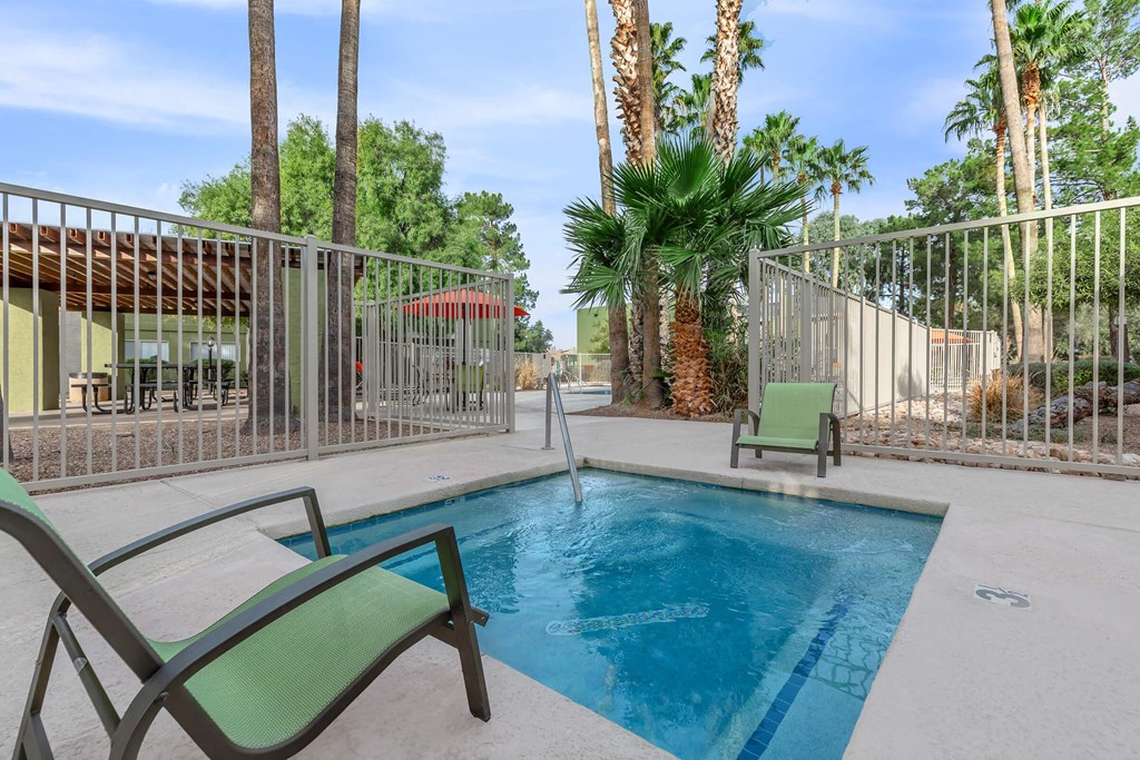 A pool surrounded by palm trees and a fence.