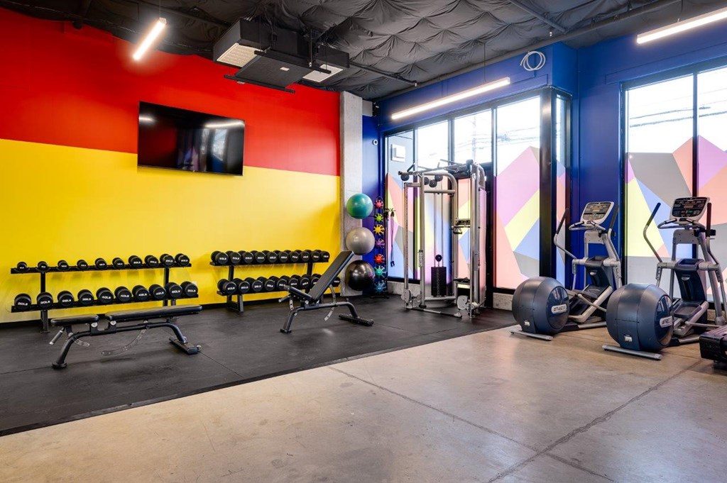MERX Slabtown gym with a variety of equipment including dumbbells, weight plates, and a bench press.