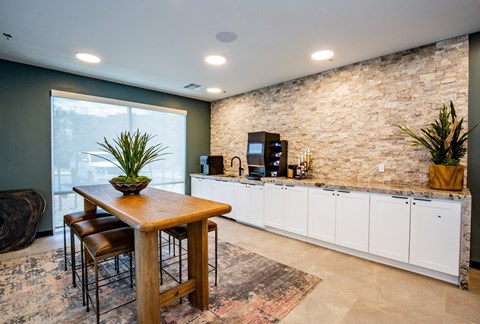 A kitchen with a wooden table and chairs in front of a stone wall.