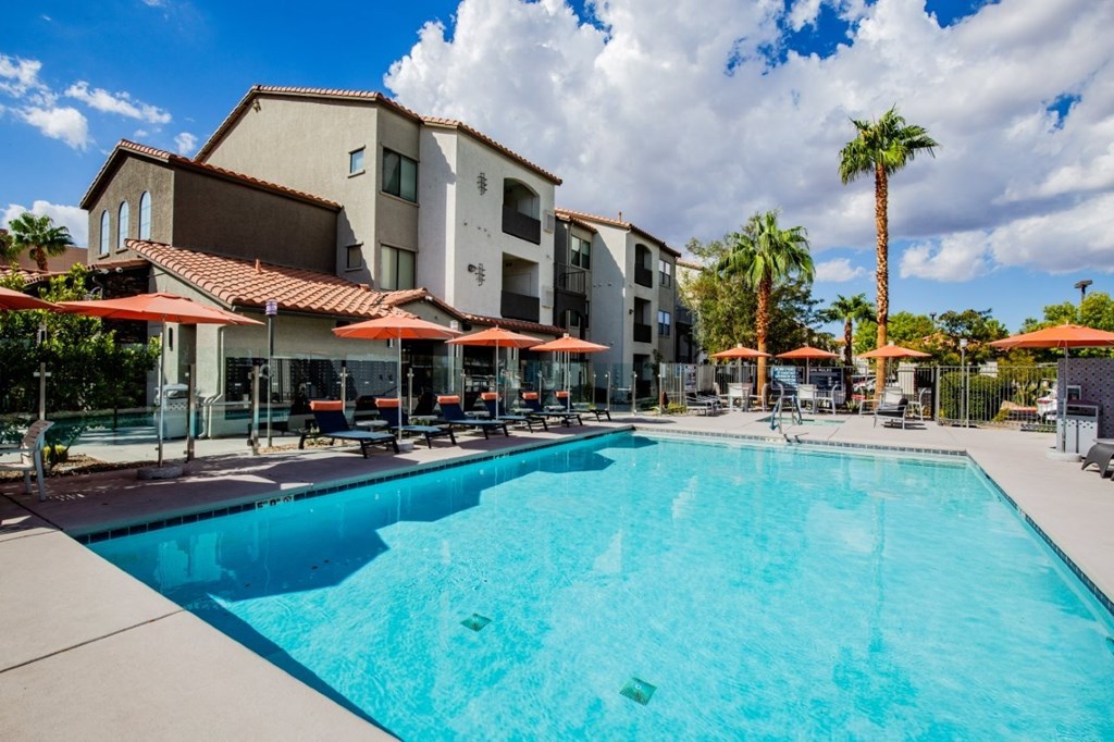 Colton Apartments large sparkling pool with seating with umbrellas