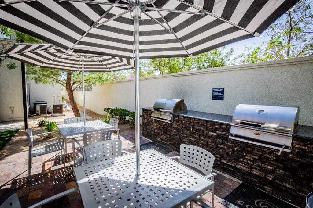 Colton Apartments seating with tables and umbrellas by BBQ