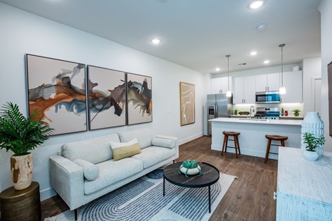 A living room with a white couch and a painting on the wall.