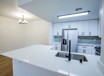 A modern kitchen with a white countertop and stainless steel appliances.