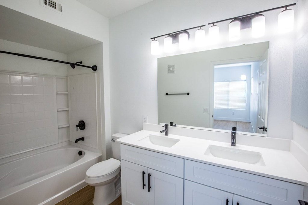 Colton Apartments bathroom with white double sinks and tub