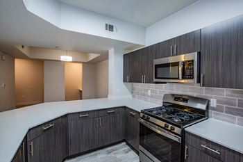 A modern kitchen with dark wood cabinets and a stainless steel oven.