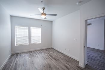 A room with a ceiling fan and wooden flooring.