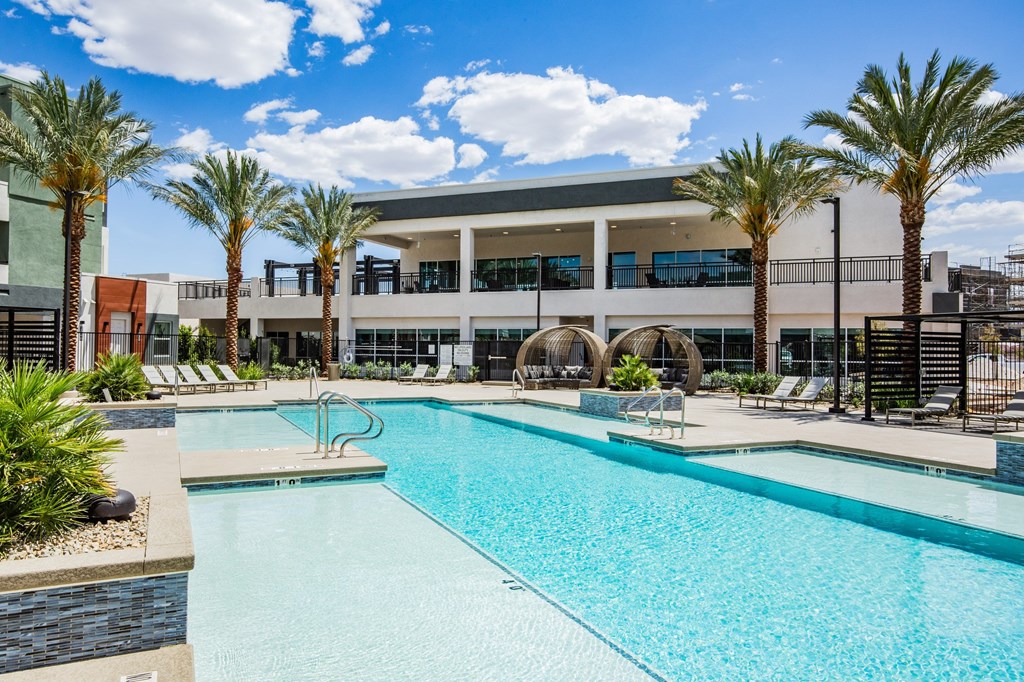 A swimming pool in front of a building with palm trees.