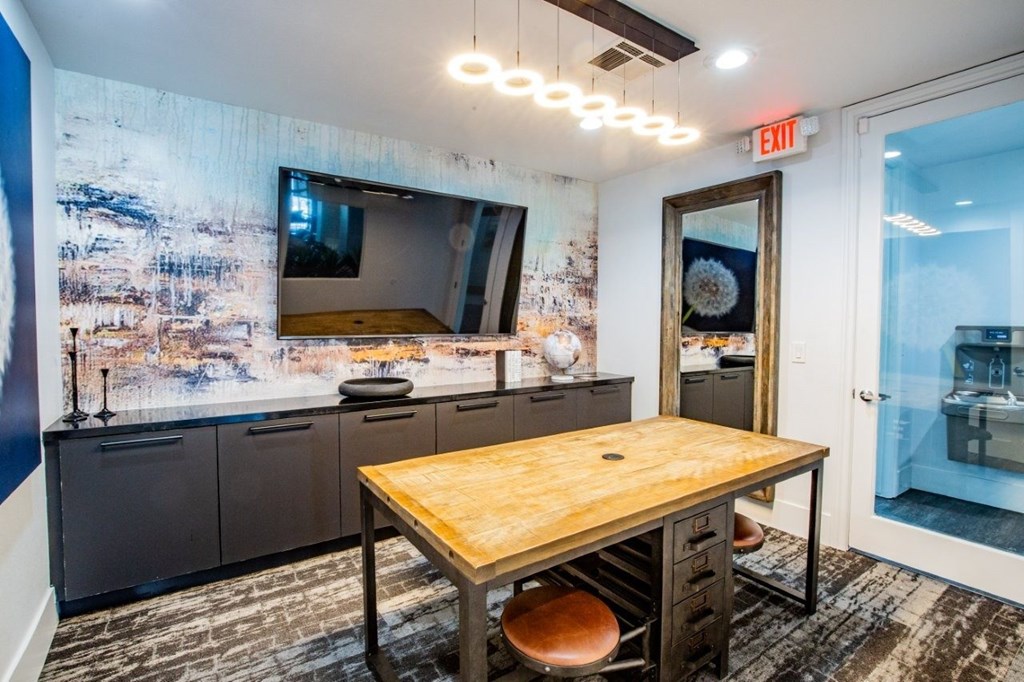 Colton Apartments A room with a wooden table and a large TV on the wall.