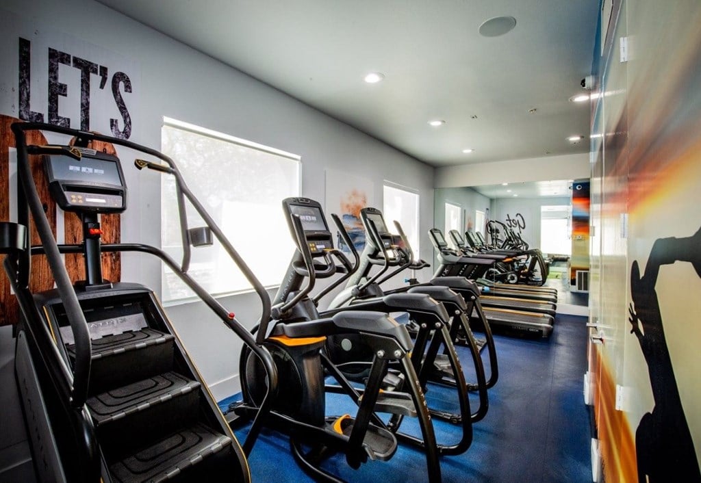 Colton Apartments A gym with treadmills and elliptical machines.