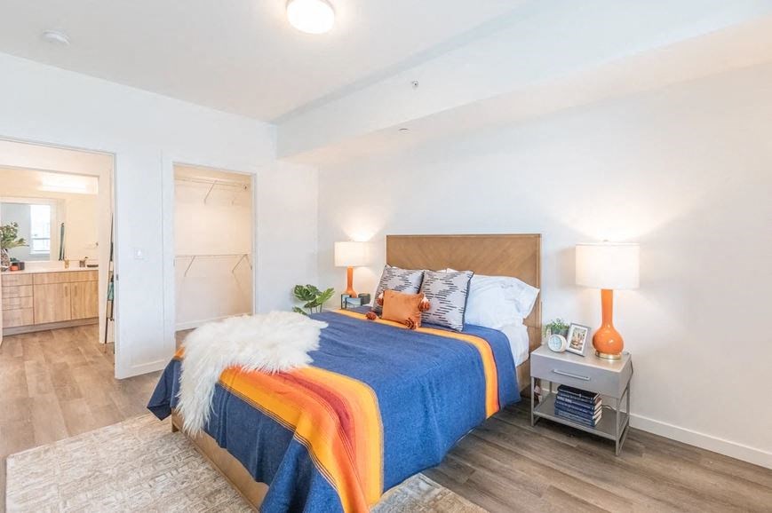 A bedroom with a bed covered in a blue and orange comforter.