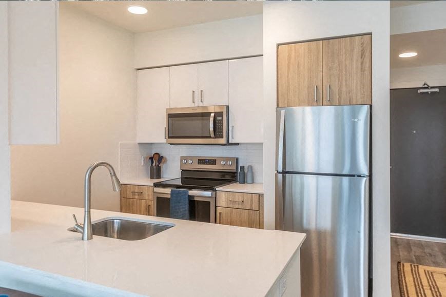 A modern kitchen with a stainless steel refrigerator and a white countertop.