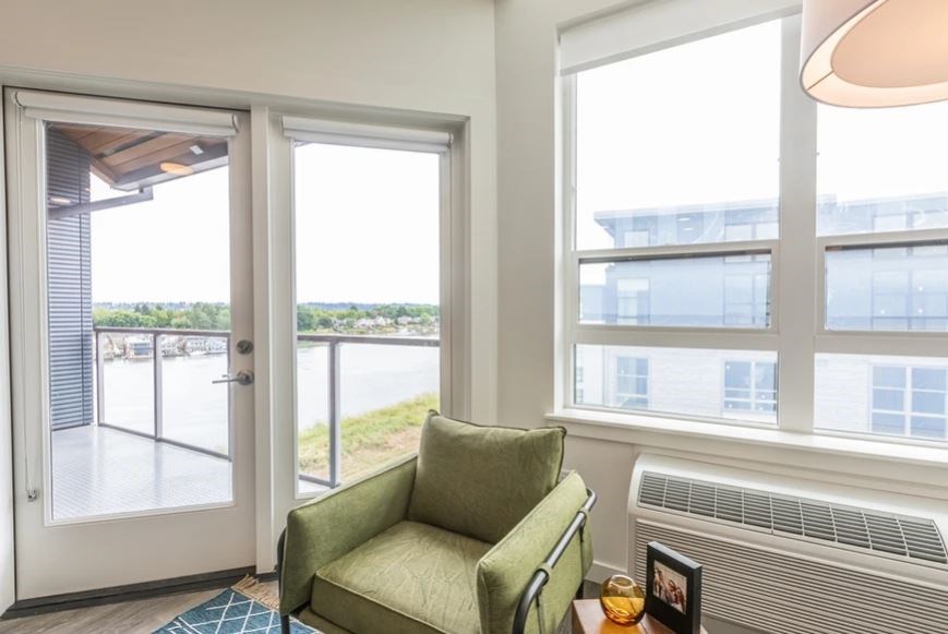 A green chair sits in a room with a view of the outside.