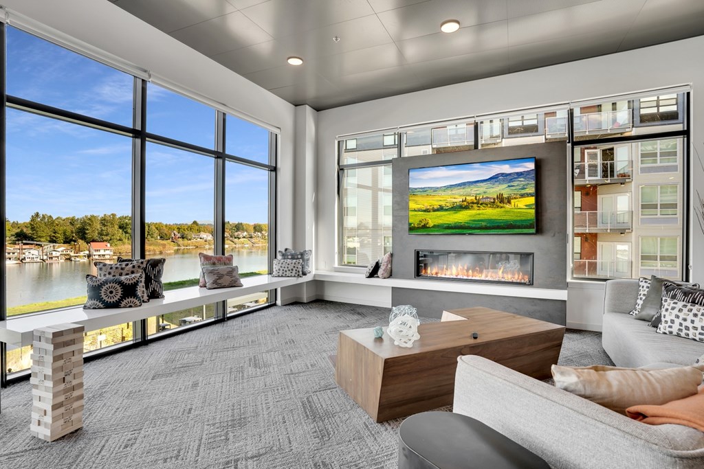 A modern living room with a fireplace and a large window overlooking a lake.