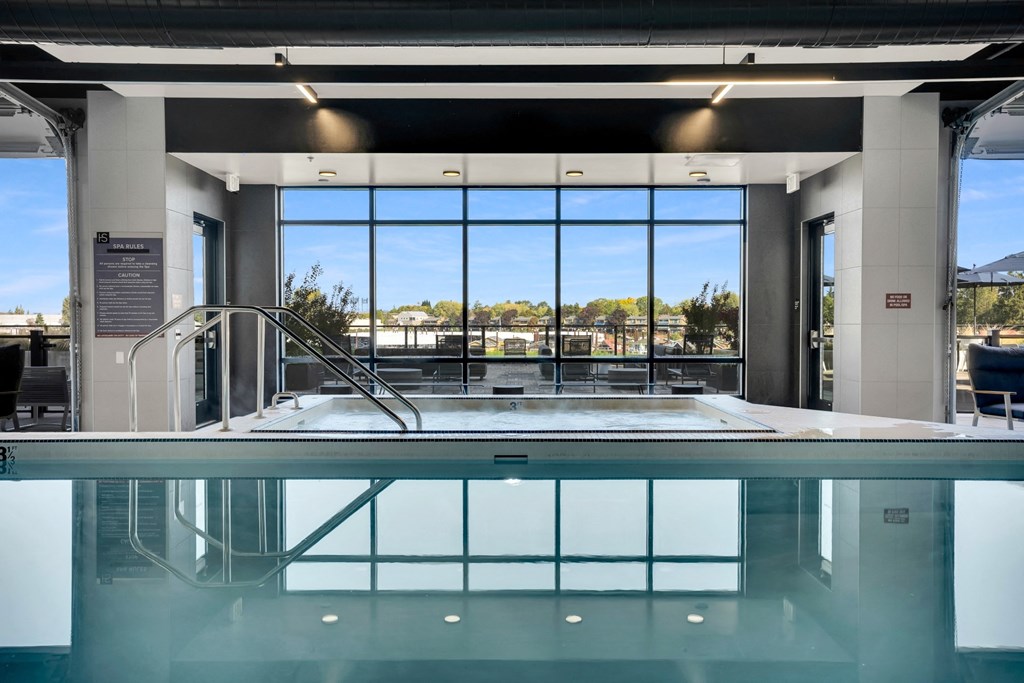 A large indoor swimming pool with a glass bottom and a view of the outdoors through the windows.