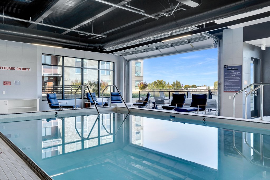 A swimming pool inside a building with a view of the outdoors.