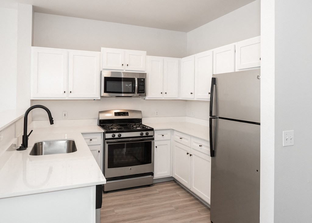 a kitchen with white cabinets and stainless steel appliances