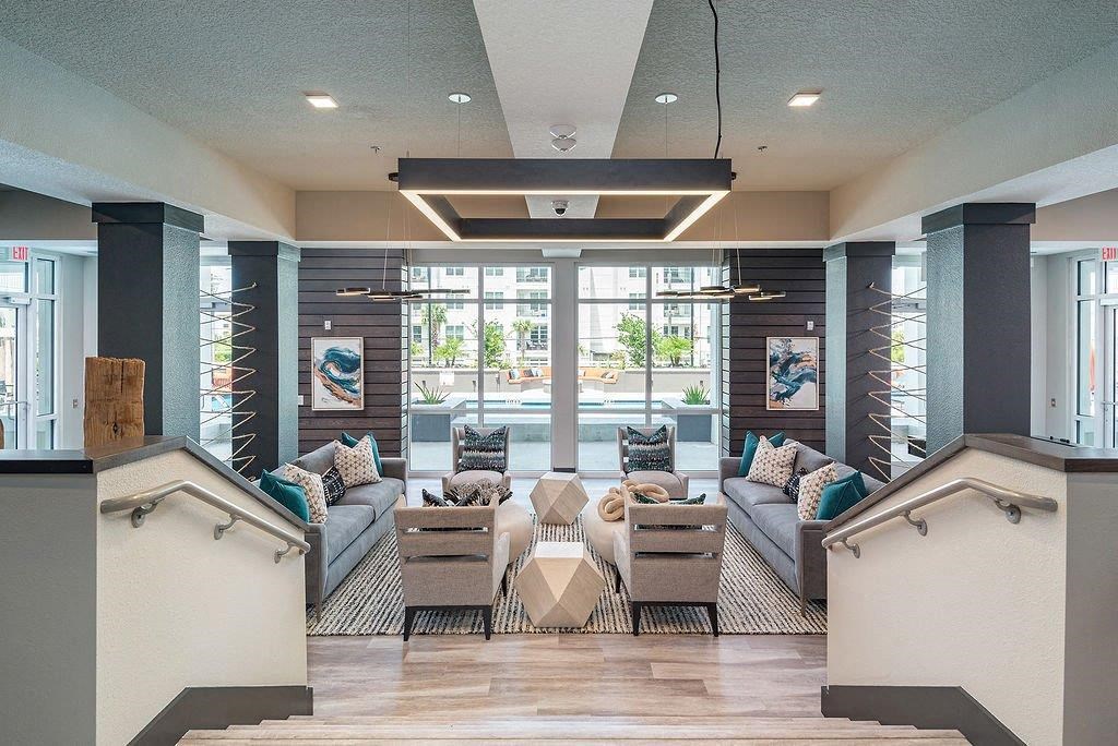 a lobby with couches and chairs and a pool in the background