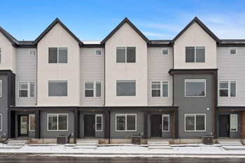 a row of apartment buildings with black doors and white siding - Photo Gallery 24