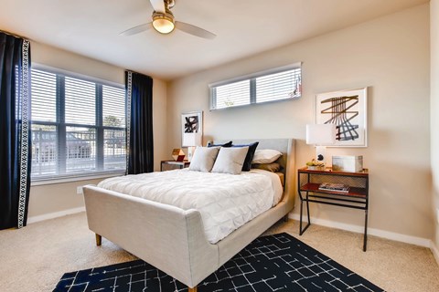 A bedroom with a large bed and a ceiling fan.