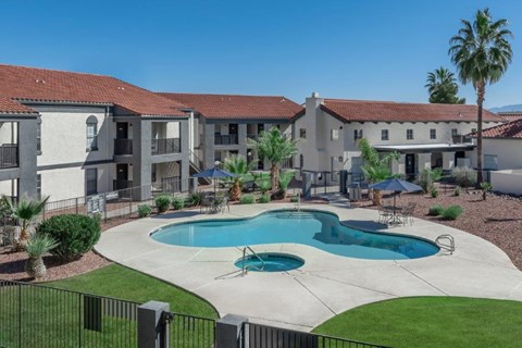A swimming pool in front of a building with a black fence around it.