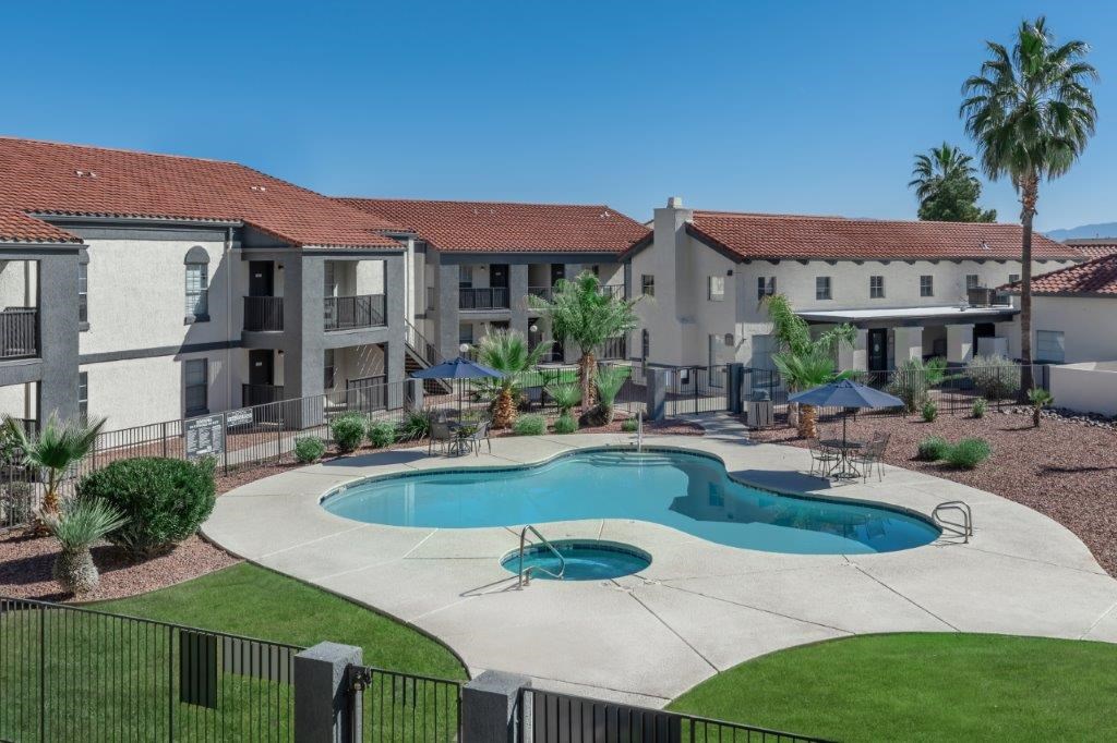 A swimming pool in front of a building with a black fence around it.