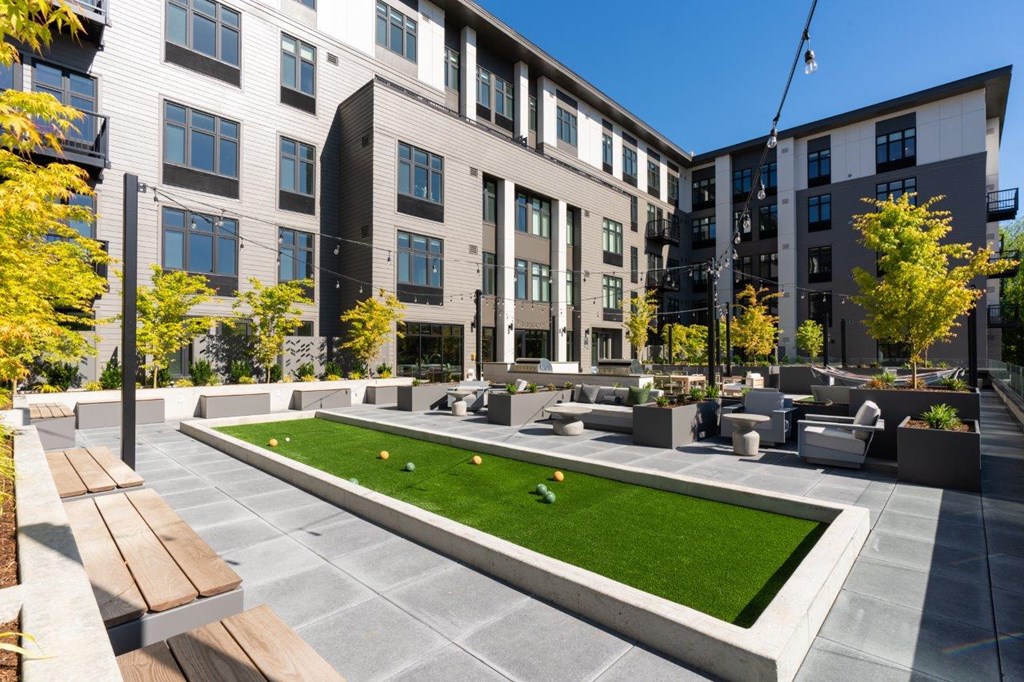 a courtyard with benches and grass in front of apartment buildings