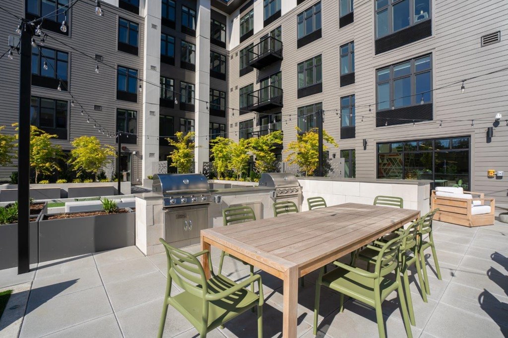 a communal patio with a table and chairs in front of an apartment building
