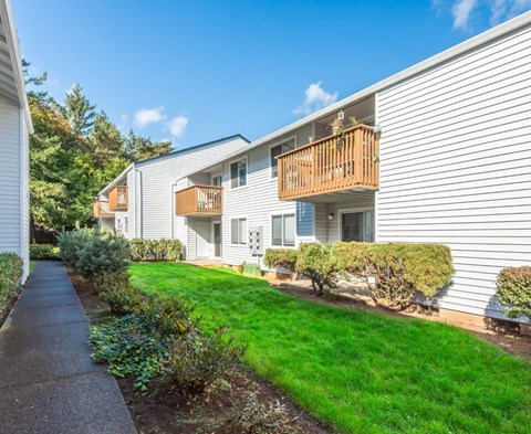 Beautiful landscaping and green grass along private balconies at Heron Hills apartments in Gresham Oregon.