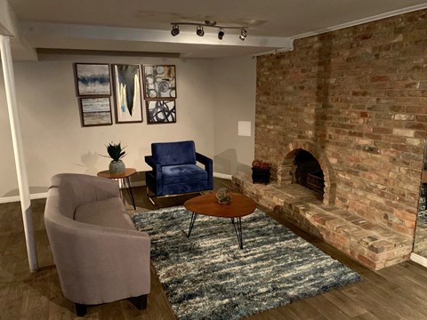 a living room with a brick fireplace and a couch and chairs