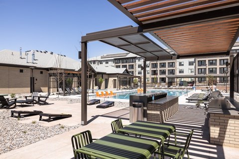 A pool area with sun loungers and a building in the background.