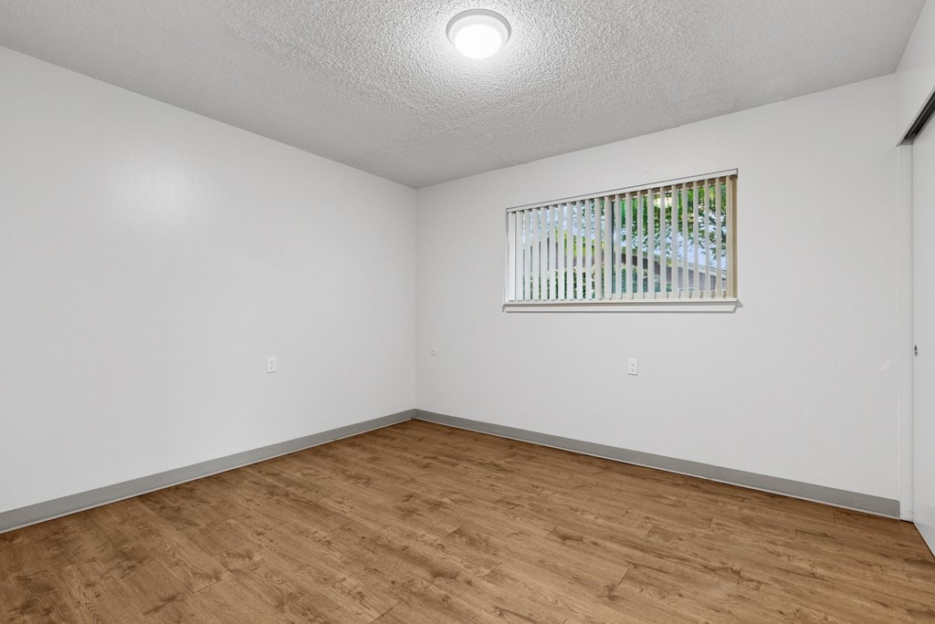 A room with a window and wooden flooring.
