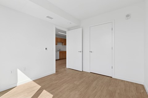 A white room with a wooden floor and two white doors.