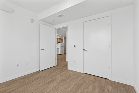 A hallway with white doors and wooden floors.