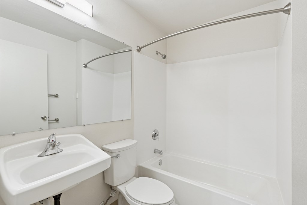A white bathroom with a toilet, sink, and bathtub.