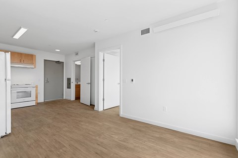 A spacious room with a white wall and a wooden floor.