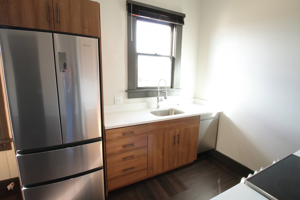 A kitchen with a stainless steel refrigerator and wooden cabinets.