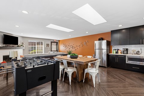 A modern kitchen with a foosball table in the middle.