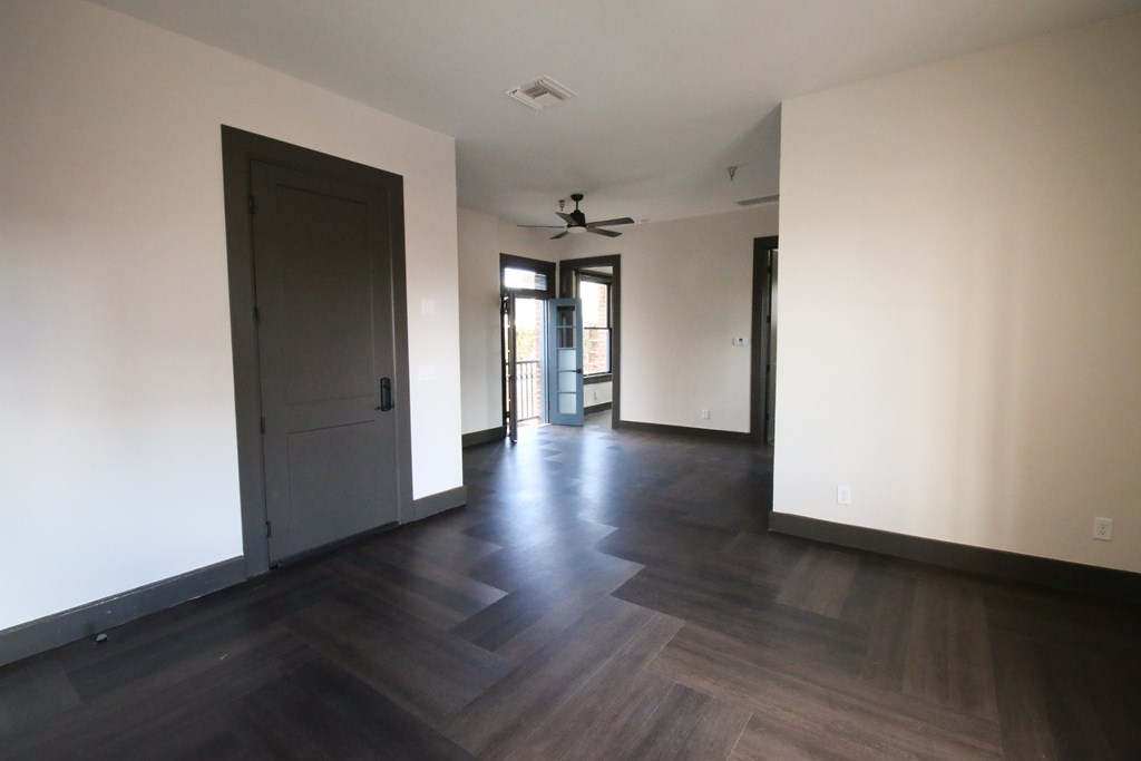 A room with a dark wood floor and a ceiling fan.