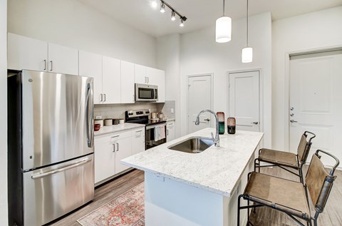 a white kitchen with stainless steel appliances and a white counter top