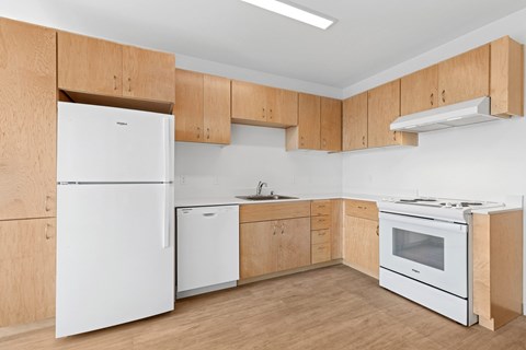 A kitchen with white appliances and wooden cabinets.