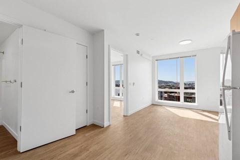A white room with a large window and wooden floors.