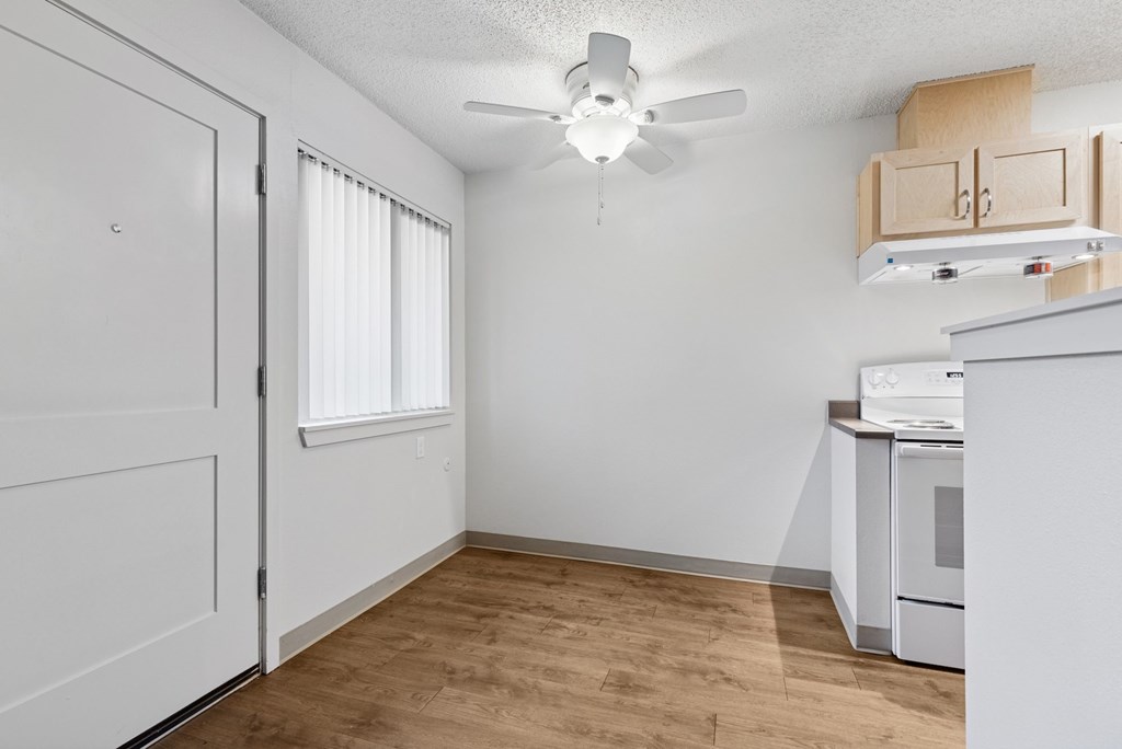 A kitchen area with a white oven and wooden flooring.
