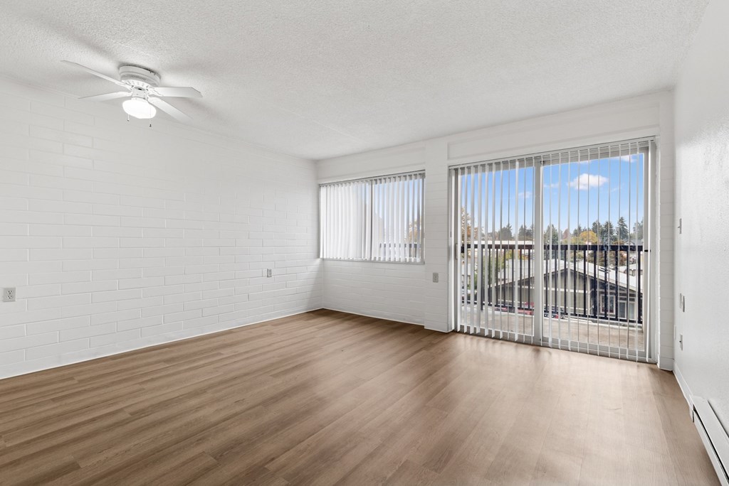 A room with a ceiling fan and sliding glass doors.