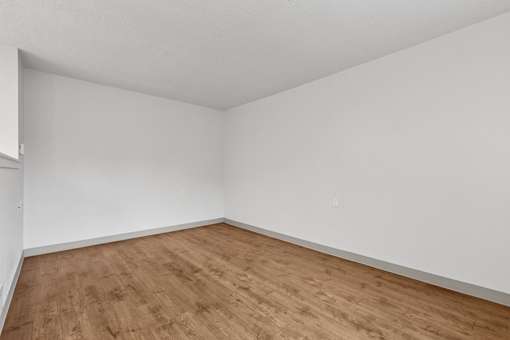 A room with wooden flooring and white walls.