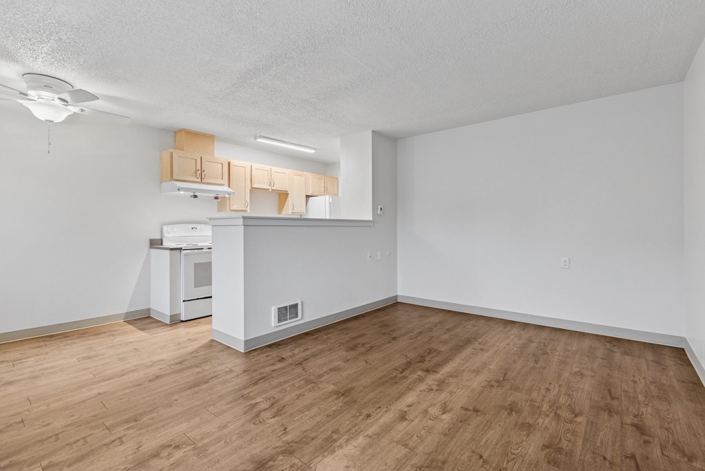 A kitchen with white appliances and wooden floors.